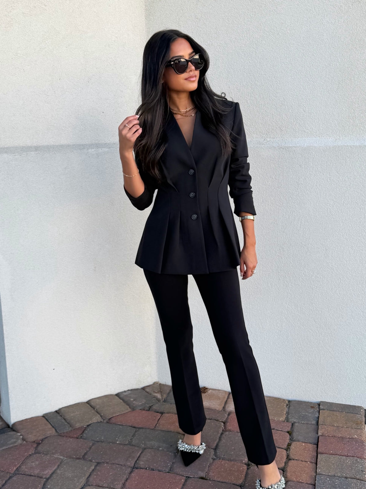 Model in a black suit against a white wall